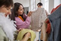 Menschen stöbern bei einem Kleidertausch durch Secondhand-Kleidung.