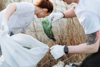Zwei Freiwillige sammeln Plastikmüll in der Natur.