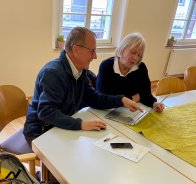 Zwei Senioren arbeiten gemeinsam an einem Laptop im Technikcafé.
