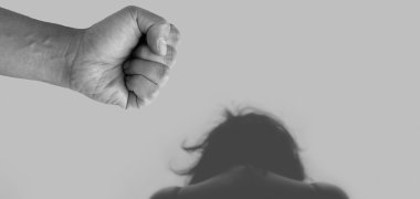 Frau gebeugt von hinten im Vordergrund eine Faust