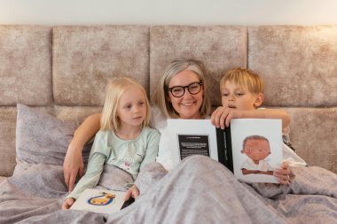 Frau liest zwei Kindern im Bett vor