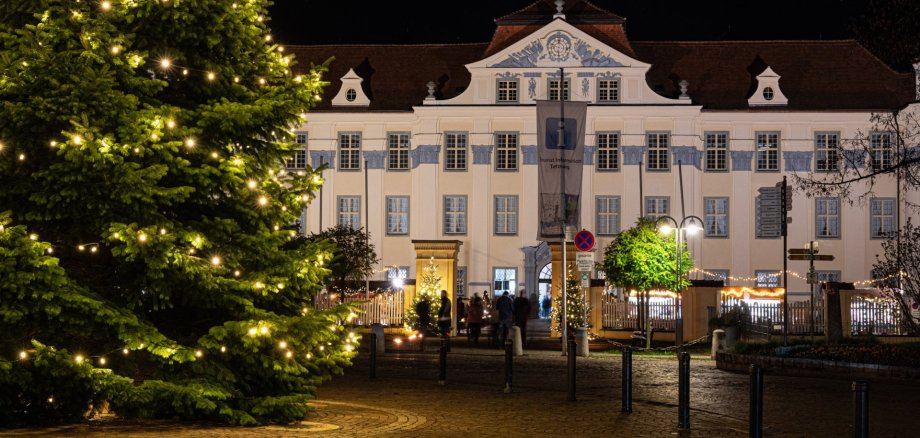 Neues Schloss Tettnang mit beleuchtetem Weihnachtsmarkt und Verkaufsbuden des Weihnachtsmarkts bei Nacht