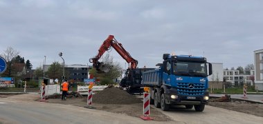 Lastwagen mit Bagger im Hintergrund auf der Baustelle des Kreisverkehrs