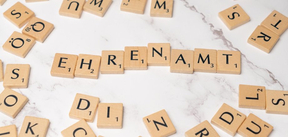 Viele Buchstabensteinchen inder Mitte das zusammengesetzte Wort Ehrenamt