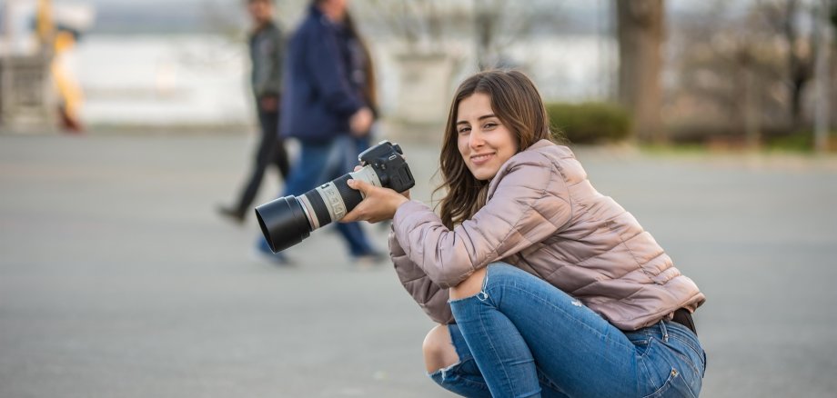 Frau hockend mit Fotoapparat