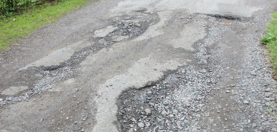 Straße mit aufgerissenem Asphalt