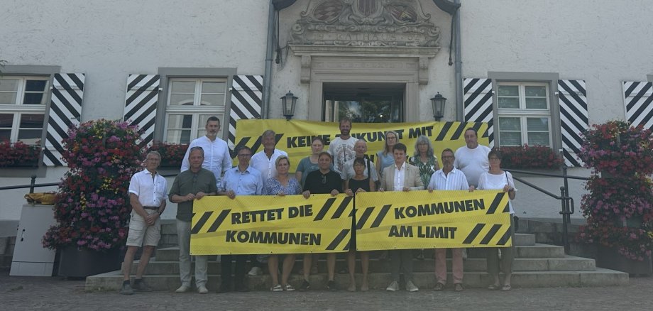 Stadtspitze und Gemeinderäte mit zwei Bannern vor dem Rathaus