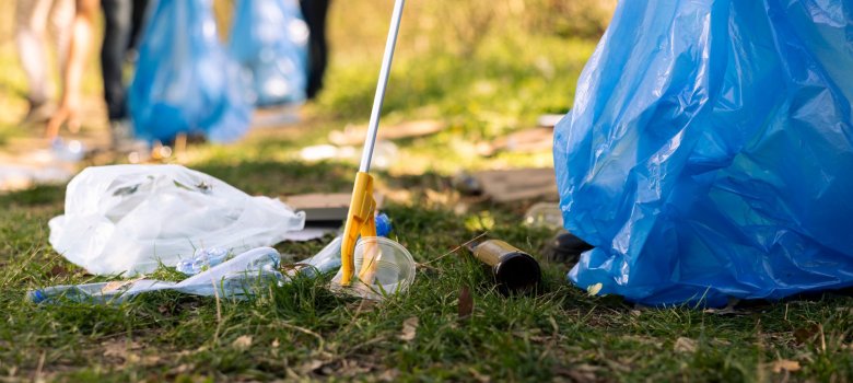 Activist using claw tool to collect rubbish and plastic junk from the ground Müll am Boden wird mit Zange in Plastiksack gesteckt