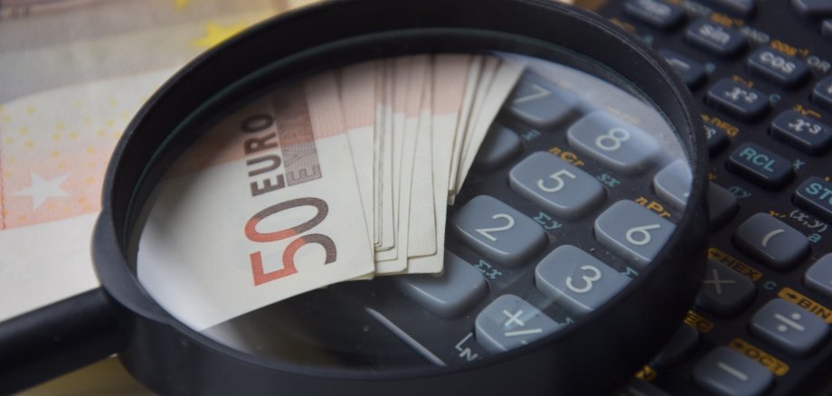 Lupe über Fünzig-Euro-Scheinen und einem Taschenrechner