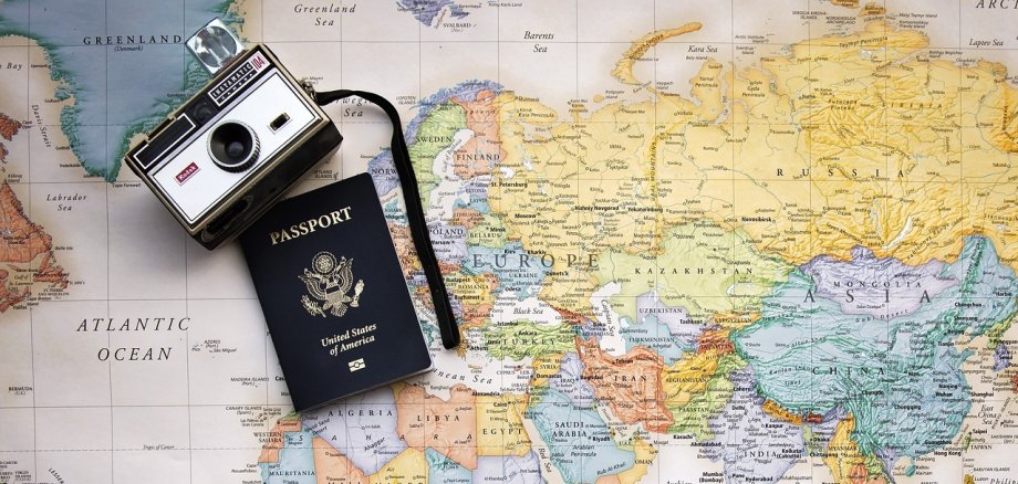 Pass und Fotoapparat liegen auf einer Weltkarte/ Bild: Pixabay