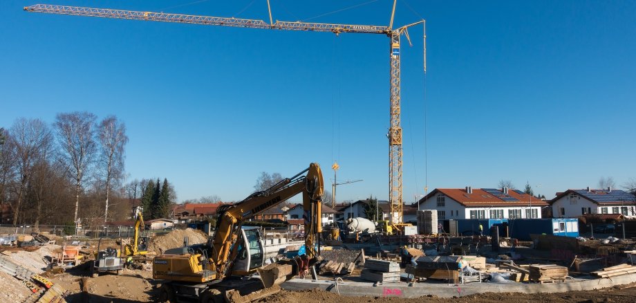 Baustelle auf Baugelände mit Kran und Bagger im Zentrum