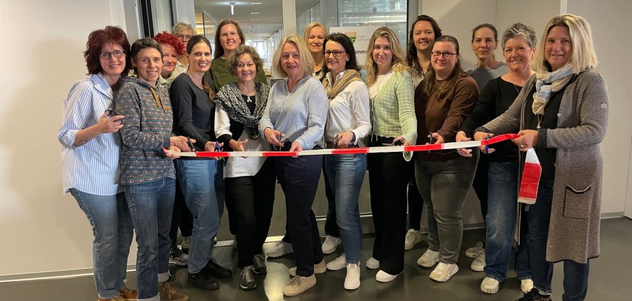 Die Mitarbeiterinnen der Stadtkämmerei durchschneiden ein rotes Band vor ihren neuen Büroräumlichkeiten