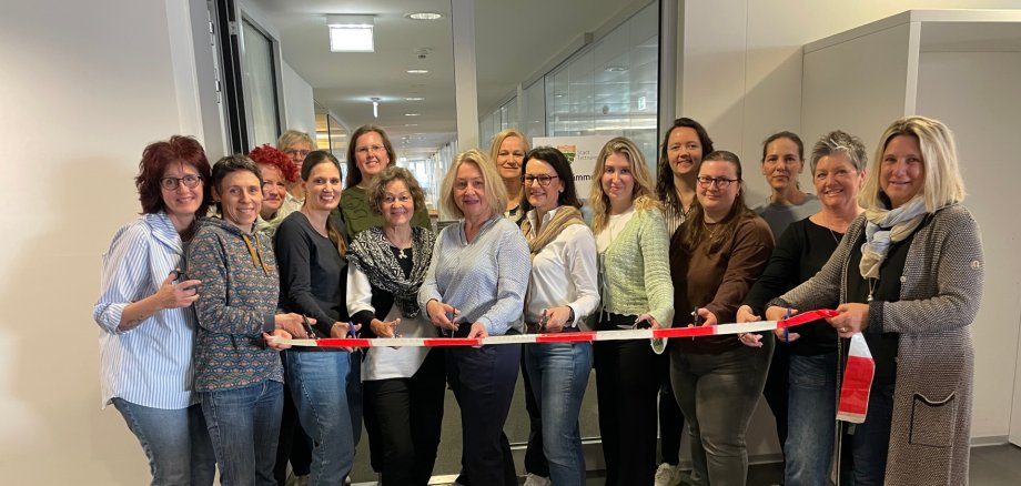 Die Mitarbeiterinnen der Stadtkämmerei durchschneiden ein rotes Band vor ihren neuen Büroräumlichkeiten