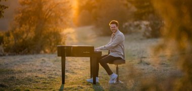 Pianist Tom Mayer am Piano im freien bei sonniger Abendstimmung