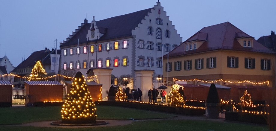 Rathaus und Kavaliersgebäude in der Dämmerung, weihnachtlich beleuchtet mit beleuchtetem Weihnachtsbaum im Vordergrund, vom Schloss aus gesehen