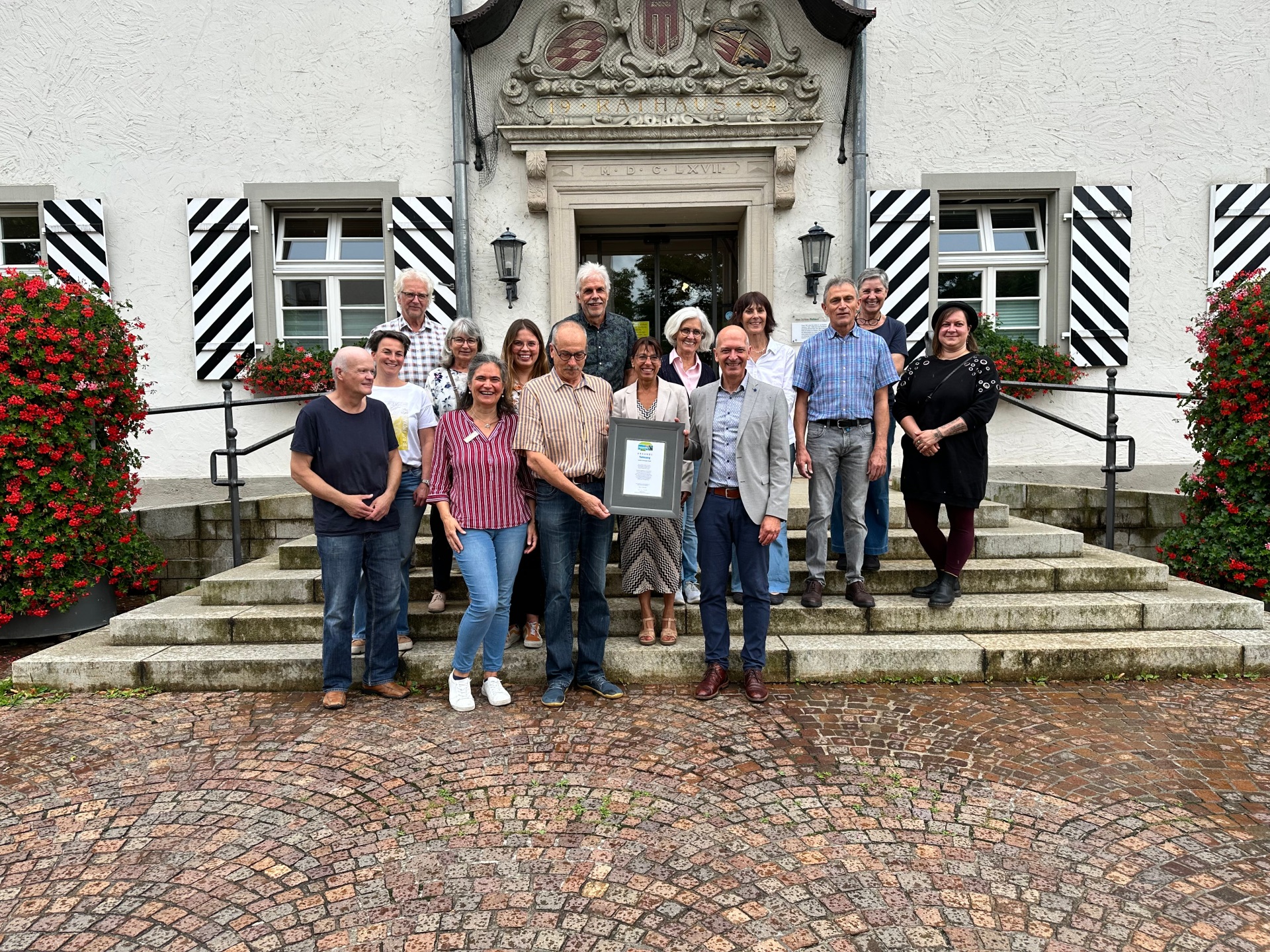 Die Teilnehmenden der Rezertifizierungsveranstaltung vor demRathaus mit der Urkunde Fairtrade Town