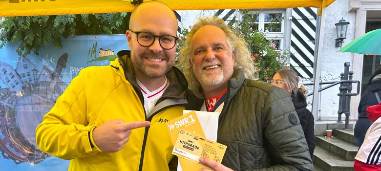 SWR!-Moderator Max Oehl übergibt die Karten zur Finalparty der SWR1 Hitparade an den Gewinner Uwe Wimmer-Kirsch
