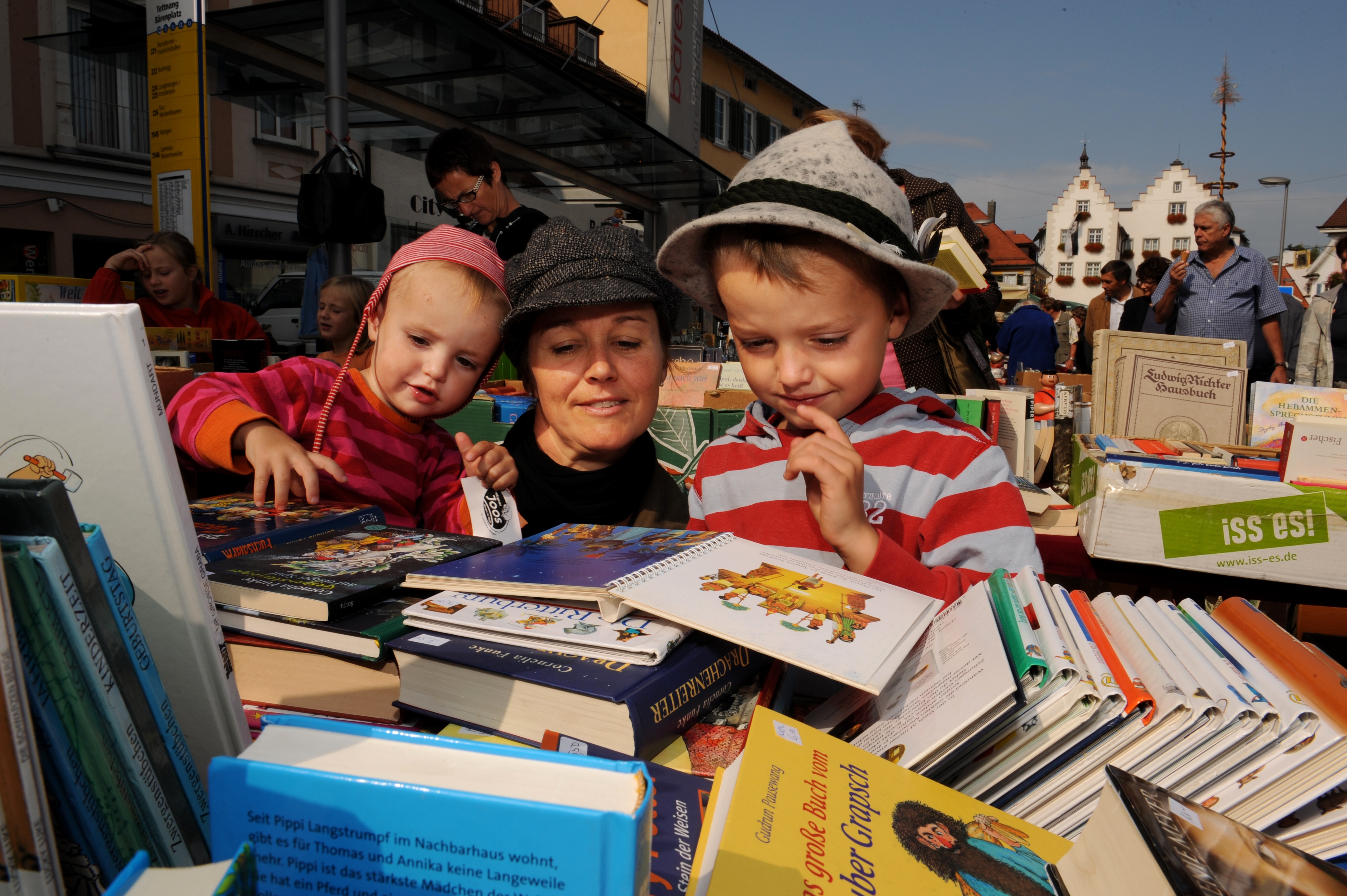 Zwei Kinder und eine Frau stöbern in Flohmarktbüchern
