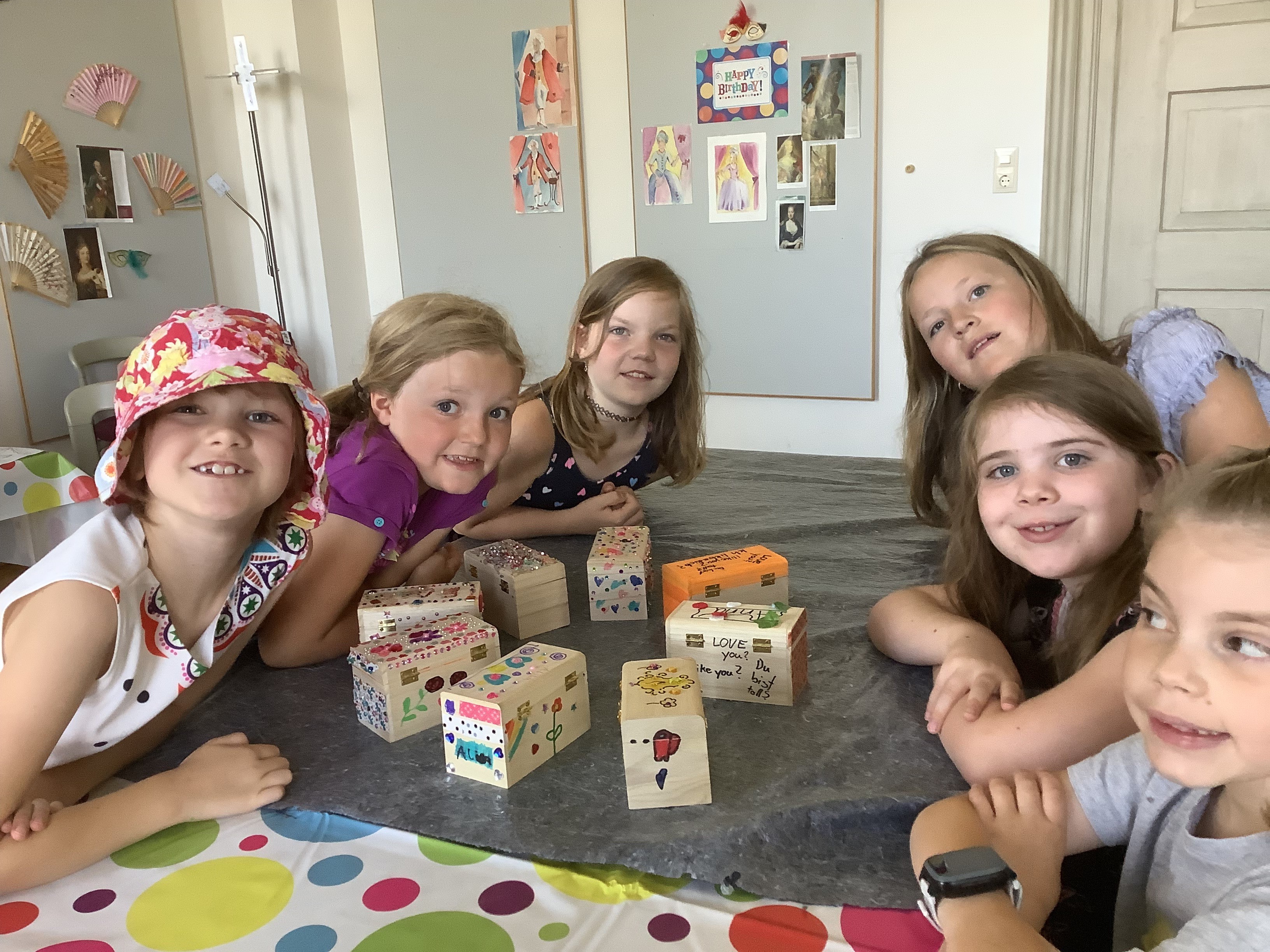 An einem Tisch sitzende Mädchen lachen in die Kamera