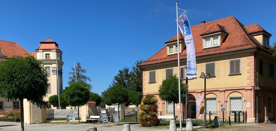 Ansicht des Gebäudes der Tourist Information mit Fahnenstange und Fahne im Vordergrund